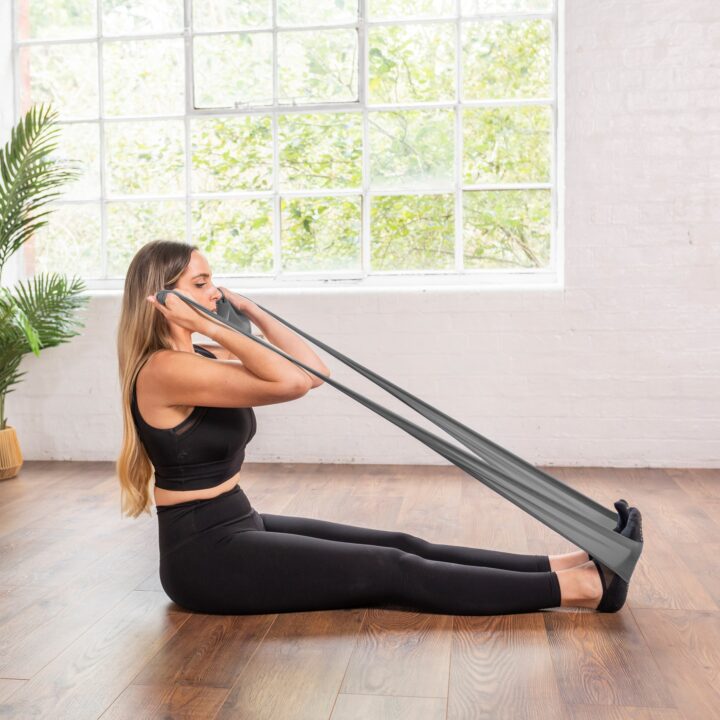 woman using grey pilates resistance band