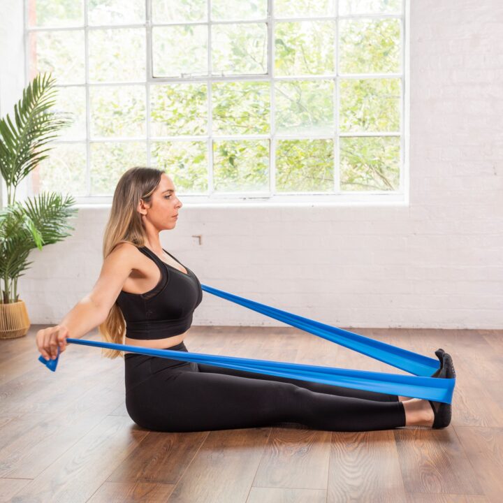Woman using blue pilates resistance band