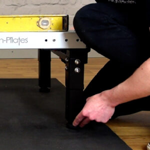 Adjusting feet to make Pilates reformer level
