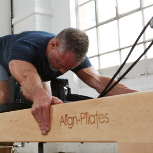Man using wooden Pilates Reformer