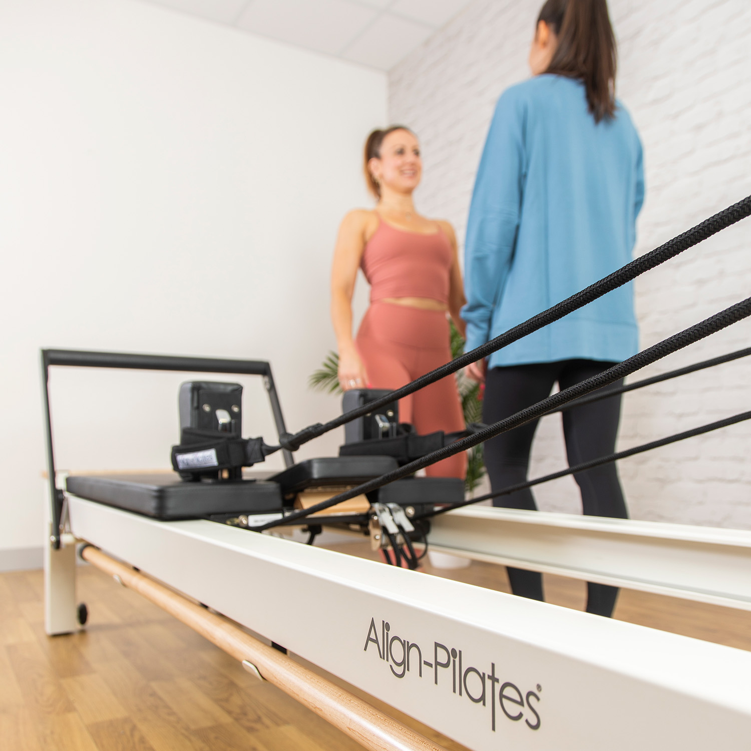 Two women talking by a Pilates Reformer