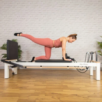 Woman using Align-Pilates C8-S Pro Pilates Reformer with Leg Extensions
